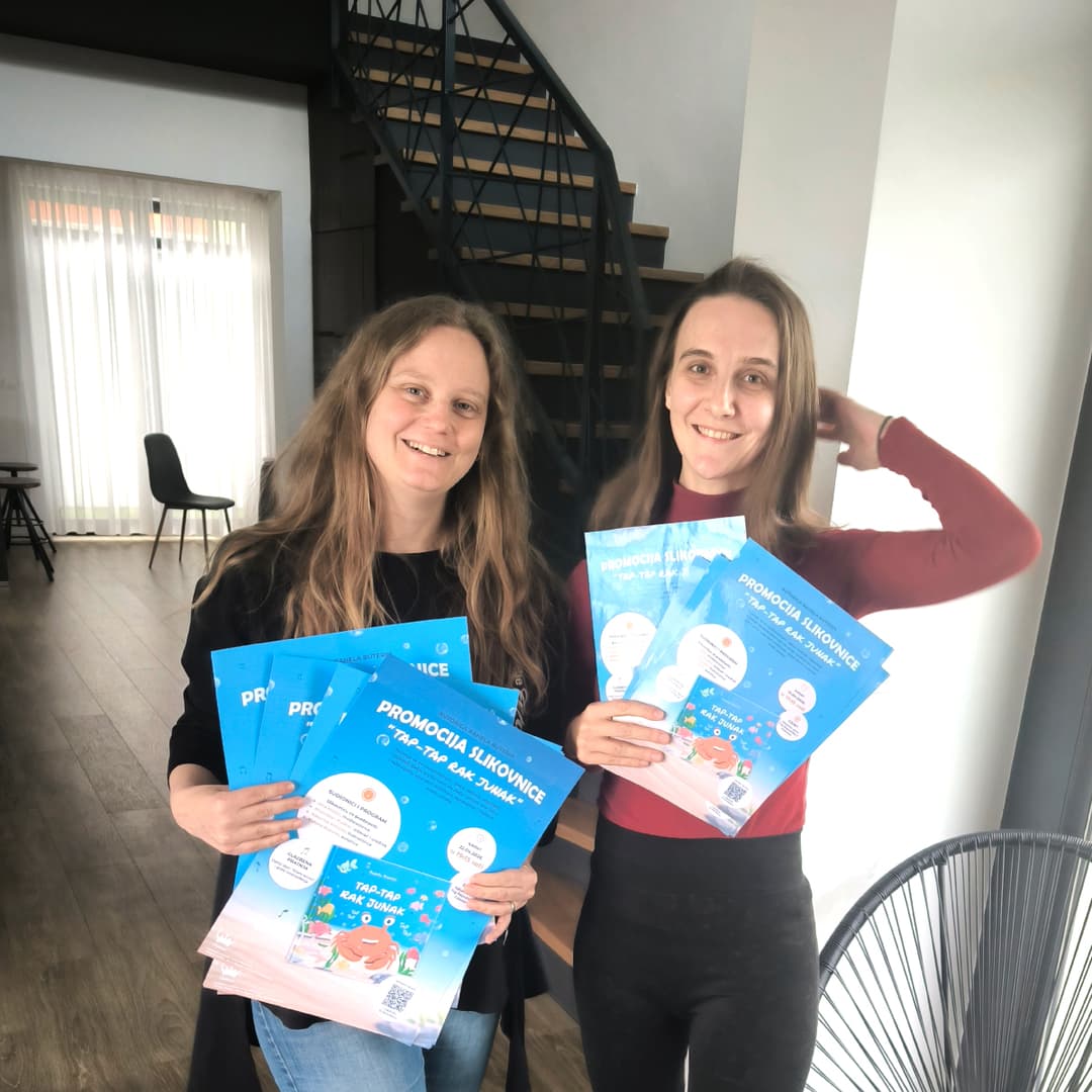 Promotivni plakat:
 - Kreiran za najavu promocije i događanja, fokusiran na jasnu komunikaciju ključnih informacija uz zadržavanje prepoznatljivog vizualnog stila slikovnice.

Vizualna dosljednost:
 - Svi materijali prate istu paletu boja i stil ilustracije, čime je postignut profesionalan i prepoznatljiv brend cijelog projekta.

Na slici možete vidjeti autoricu i mene kako nestrpljivo krećemo u promotivne aktivnosti naše prve zajedničke slikovnice